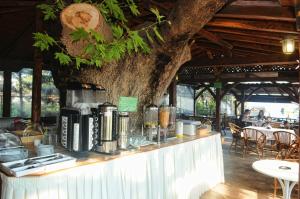 a table in a restaurant next to a tree at Haus Platanos Apartments & Bungalows by the Sea in Vourvourou