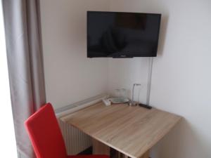 a room with a wooden table with a television on the wall at Pension Rammert in Großbettlingen