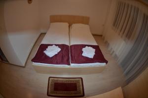Una cama pequeña con sábanas rojas y blancas. en Popas Azuga, en Azuga