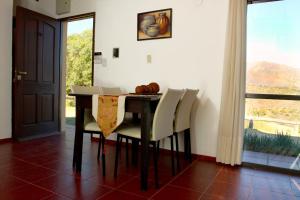 comedor con mesa, sillas y ventana en Huerta Grande Cabañas en Huerta Grande