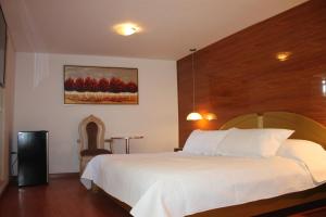 1 dormitorio con 1 cama blanca grande y cabecero de madera en Estela de Oro Hotel Boutique, en Arequipa