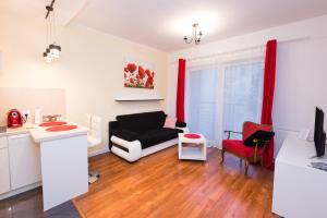 シュチェチンにあるSupreme Apartments Vossaのリビングルーム(黒いソファ、赤いカーテン付)