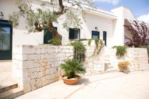 a white house with a stone wall and a tree at Masseria Asciano in Ostuni