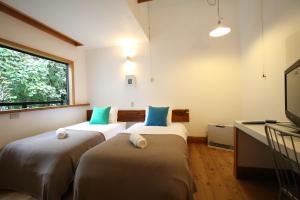 two beds in a room with a window at Momiji in Otari