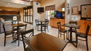a restaurant with tables and chairs and a kitchen at Best Western Gardendale in Gardendale