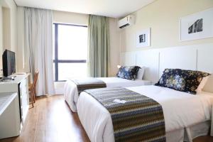 a hotel room with two beds and a television at Vitória Hotel Convention Paulínia in Paulínia