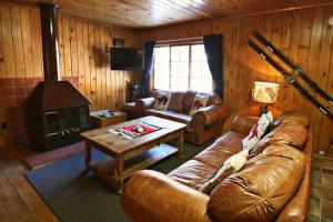 a living room with a leather couch and a fireplace at Three Bears Lodge in Red River