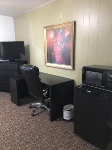 a room with a desk and a chair and a television at Grizzly Motel in Swan Hills