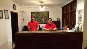 zwei Männer in roten Hemden stehen an einem Tresen in der Unterkunft Bladok Hotel & Restaurant in Yogyakarta