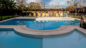 a swimming pool with chairs and blue water at Pro Hotel in Pilar