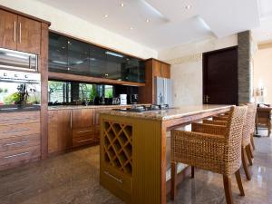 uma cozinha com armários de madeira e um bar com cadeiras em Villa LeGa em Seminyak