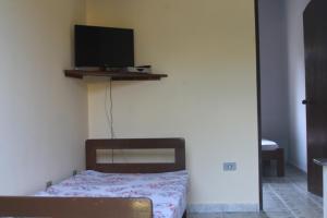 a bedroom with a bed and a tv on the wall at Oásis Pousada in Bertioga