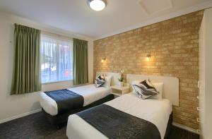 a hotel room with two beds and a brick wall at Pelicans Albany Middleton Beach in Albany