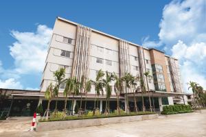 a building with palm trees in front of it at Veethara Boutique Hotel in Udon Thani
