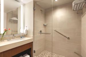 a bathroom with a shower, sink, and mirror at Hyatt House Virginia Beach / Oceanfront in Virginia Beach