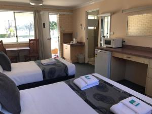 a room with two beds and a kitchen with a counter at The Edgewater at Burrill in Ulladulla