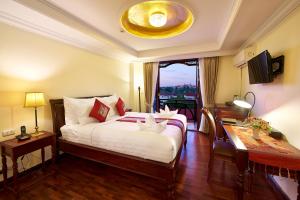 1 dormitorio con cama, escritorio y ventana en Phasouk Vien Chantra Hotel, en Vientiane