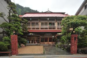 um grande edifício com árvores em frente em Atarashiya Ryokan em Tenkawa