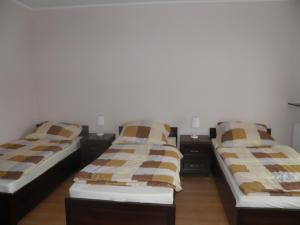 two twin beds in a room with two tables at Pensjonat Zofia Demska in Brzeg