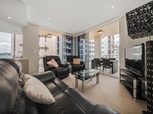 a living room with a leather couch and a television at Link Portside Wharf Apartment Hotel in Brisbane