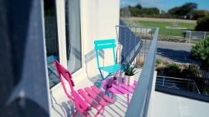 two pink and blue chairs sitting on a balcony at Hotel-Restaurant Lann Roz / Côte Cuisine in Carnac