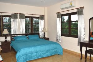 a bedroom with a blue bed and windows at Kate House Bangsaphan in Bang Saphan