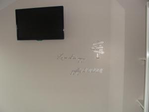 una pared con TV y un dibujo de una copa de vino en Chambres d'hôtes Sébastien en Ruaudin