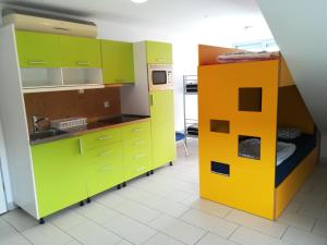 a kitchen with green and yellow cabinets and a bunk bed at Simbol Rooms with free private parking in Ljubljana