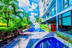 a building with a swimming pool and chairs next to a building at Tree Boutique Residence - Quiet Oasis - Stunning View, Pool & Gym in Chiang Mai