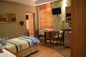 1 dormitorio con 2 camas y cocina con mesa en Le Chateau Guest House and Conference Centre, en Kempton Park