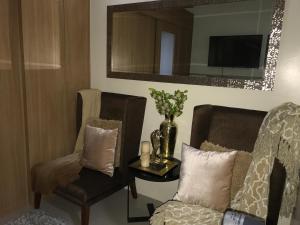 a living room with two chairs and a table and a mirror at BEST Q CONDO w/ Great View in Manila