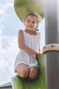 
a little girl sitting on top of a wooden bench at Vakantiedorp Marinapark in Westende
