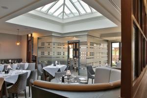 ein Restaurant mit weißen Tischen und Stühlen und einem Dachfenster in der Unterkunft Manor Hotel Solihull, BW Signature Collection in Bickenhill
