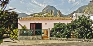 una pequeña casa blanca con montañas en el fondo en Finca Piñero, en Hermigua