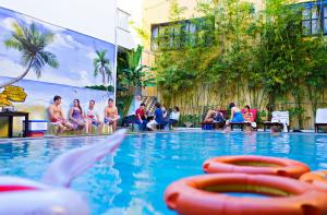 a group of people sitting around a swimming pool at Hoi An Hai Au Boutique Hotel in Hoi An