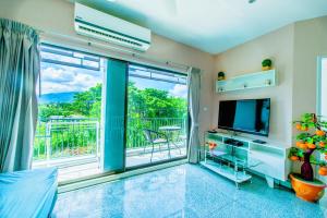 a living room with a tv and a large window at Tree Boutique Residence - Quiet Oasis - Stunning View, Pool & Gym in Chiang Mai
