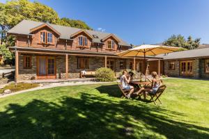 un grupo de personas sentadas en una mesa frente a una casa en Wanaka Homestead Lodge & Cottages, en Wanaka