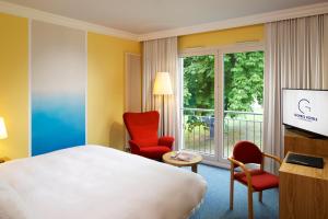 a hotel room with a bed and chairs and a tv at Hotel Parc Plaza in Luxembourg