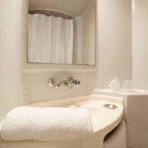 a white bathroom with a sink and a mirror at Premiere Classe Evreux in Évreux
