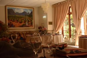 a dining room with wine glasses and a painting on the wall at Le Chateau Guest House and Conference Centre in Kempton Park