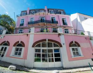 a pink building with a balcony on top of it at Safestay Lisbon Bairro Alto in Lisbon