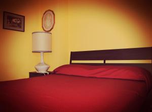 a bedroom with a red bed and a lamp at Casa Vacanze Zia Titina in Trabia