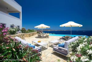 a patio with chairs and umbrellas and a pool at Slow Luxury Patmos Villas Sophia and Tatyana with private pools in Grikos