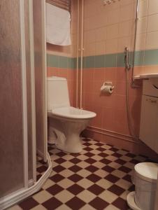 a bathroom with a toilet and a shower with a checkered floor at Savonlinnan Kansanopisto - Wanha Pappila in Savonlinna +36 photos