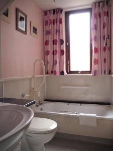 een badkamer met een bad, een toilet en een raam bij Corbie Self Catering Shetland in Lerwick