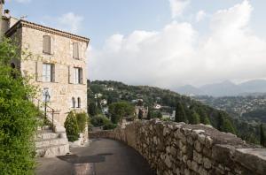 a stone building and a stone wall next to a road at La Maison de Jacques Prevert in Vence