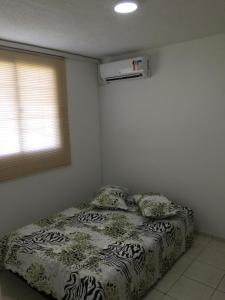 a bedroom with a bed with a comforter and a window at Apartamento-Excelente localização in Resende