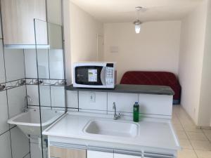 eine Küche mit einer Spüle und einer Mikrowelle auf der Theke in der Unterkunft Apartamento-Excelente localização in Resende
