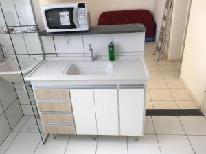 a kitchen with a white sink and a microwave at Apartamento-Excelente localização in Resende