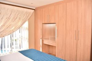 a bedroom with wooden cabinets and a bed with a window at Homestay Travel Guest House in Roodepoort
